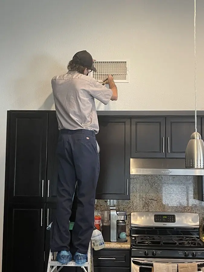 Technician inspecting an air vent during HVAC service in Southeast Arcadia